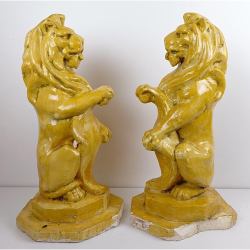 1115 - A pair of yellow glazed lion finials, various losses, 63 cm high (2)