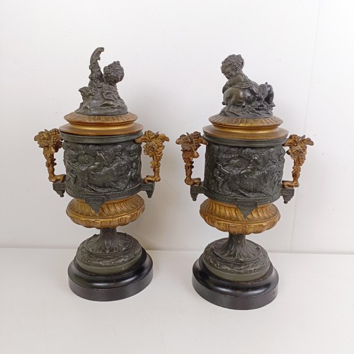 1080 - A pair of brass and bronze urns, with covers, with cherub finials on wooden bases, 40 cm high (2)