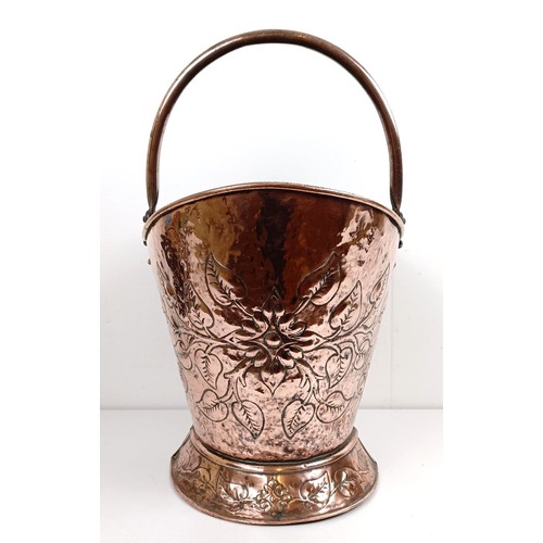 1123 - A copper coal scuttle, embossed with flowers, 42 cm wide, a pair of fire irons, and assorted metalwa... 