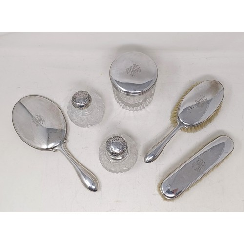 419 - A Danish silver coloured metal part dressing table set, comprising a hand mirror, two brushes, a sil...