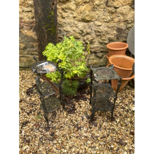 1294 - A painted metal garden bench, 117 cm wide, a pair of pot stands, and a metal garden urn with plants