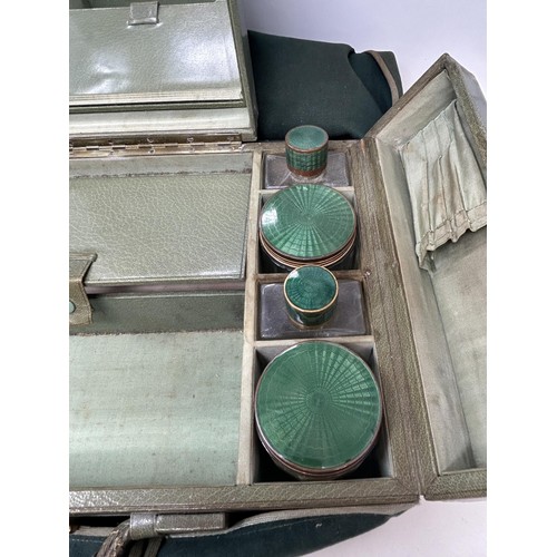 844 - An Art Deco travelling dressing case, the glass jars with enamel decoration, in a green leather trav... 