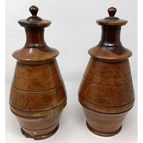 717 - A pair of turned lignum vitae urns and cover, 30 cm high (2)