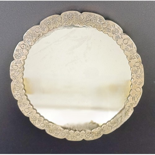 768 - An Indian silver coloured metal hand mirror, 16 cm diameter, another, decorated flowers, 22 cm wide,... 