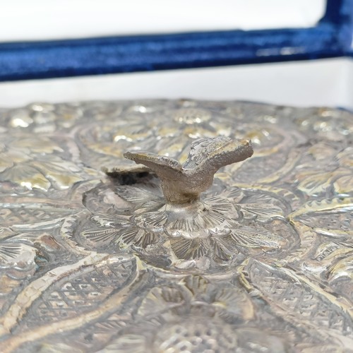 768 - An Indian silver coloured metal hand mirror, 16 cm diameter, another, decorated flowers, 22 cm wide,... 