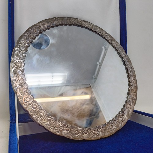 768 - An Indian silver coloured metal hand mirror, 16 cm diameter, another, decorated flowers, 22 cm wide,... 