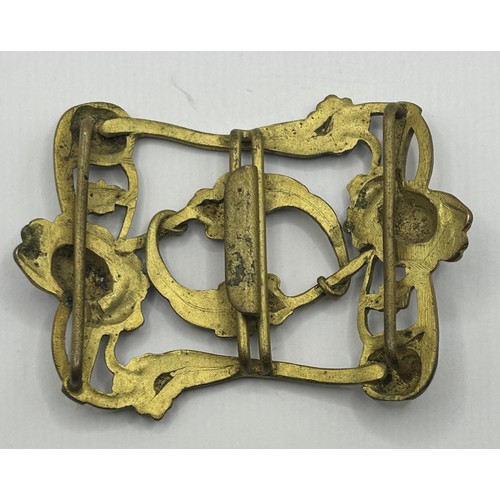 723 - A gold plated token dated 1911, with mount cut, an Art Nouveau gilt metal and enamel buckle, decorat... 