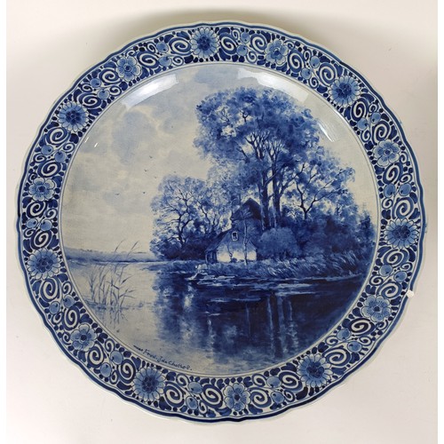 744 - A large Delft blue and white plate, decorated figures fishing, 41 cm diameter, and another, decorate... 