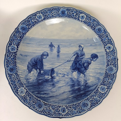 744 - A large Delft blue and white plate, decorated figures fishing, 41 cm diameter, and another, decorate... 