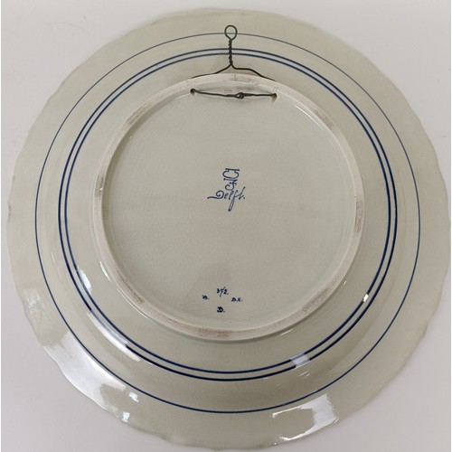 744 - A large Delft blue and white plate, decorated figures fishing, 41 cm diameter, and another, decorate... 