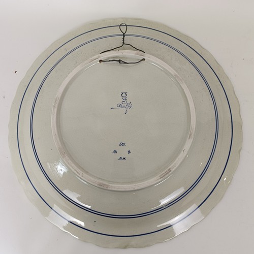 744 - A large Delft blue and white plate, decorated figures fishing, 41 cm diameter, and another, decorate... 