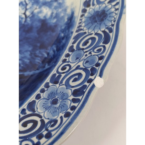 744 - A large Delft blue and white plate, decorated figures fishing, 41 cm diameter, and another, decorate... 