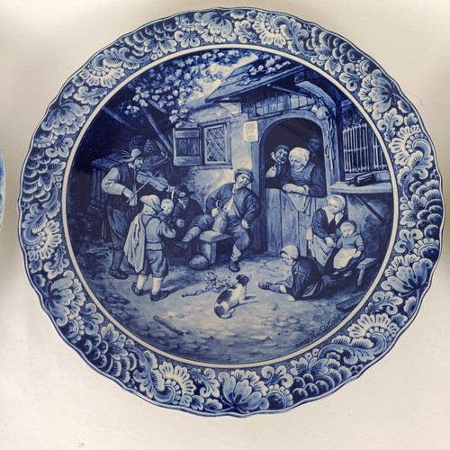 747 - A Delft blue and white plate, decorated mother and children, 34 cm diameter, another, decorated tave... 