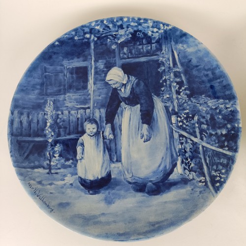 747 - A Delft blue and white plate, decorated mother and children, 34 cm diameter, another, decorated tave... 