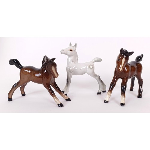 611 - A Beswick figure of Red Rum, on a mahogany base, 31 cm high and three Beswick foal figures (4)