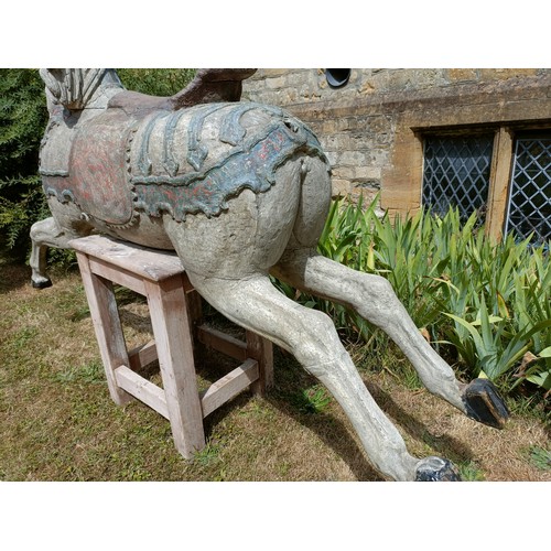 619 - A large and impressive carved wood and painted carousel horse, on a later stand, 190 cm wide