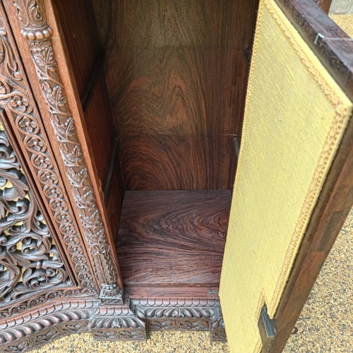 971 - A 19th century Burmese serpentine shaped front cabinet, with carved and pierced decorated and having... 