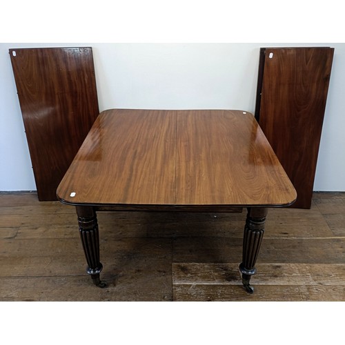 997 - A 19th century mahogany extending dining table, on turned reeded tapering legs to casters, the top, ... 