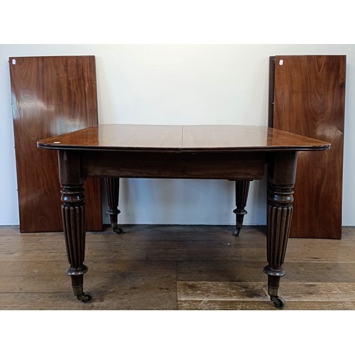 997 - A 19th century mahogany extending dining table, on turned reeded tapering legs to casters, the top, ... 