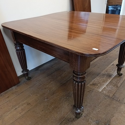 997 - A 19th century mahogany extending dining table, on turned reeded tapering legs to casters, the top, ... 