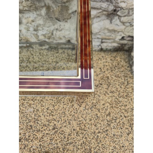 1015 - A brass and lacquered two tier table, with a glass shelf, 128 cm wide