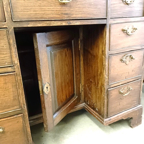 983 - An oak kneehole desk, with a brushing slide and nine drawers, 92 cm wide