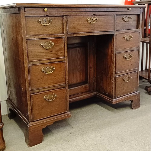 983 - An oak kneehole desk, with a brushing slide and nine drawers, 92 cm wide