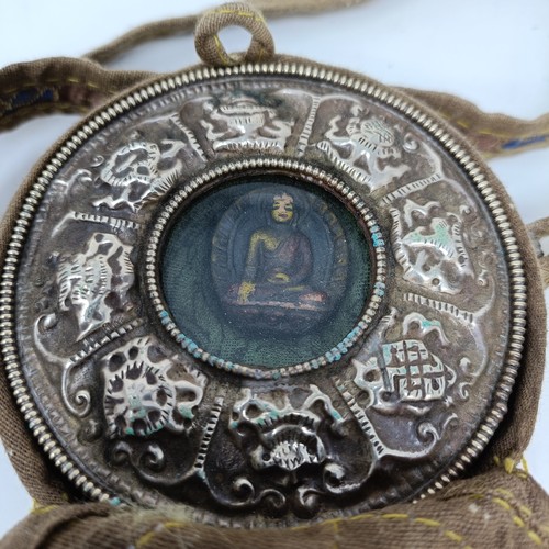 An Eastern silver coloured metal relic, in a silk purse