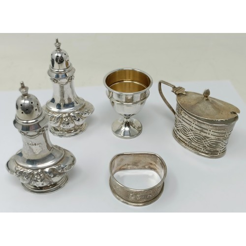 A pair of silver pepperettes, a silver mustard, a silver egg cup and a ...