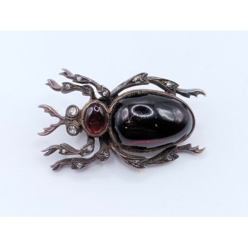 684 - A late 19th/early 20th century silver coloured metal and red paste bug brooch