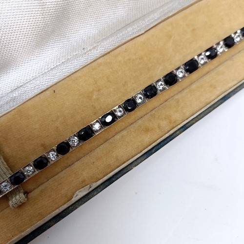 717 - A sapphire and white stone tennis bracelet, in a vintage jewellery box