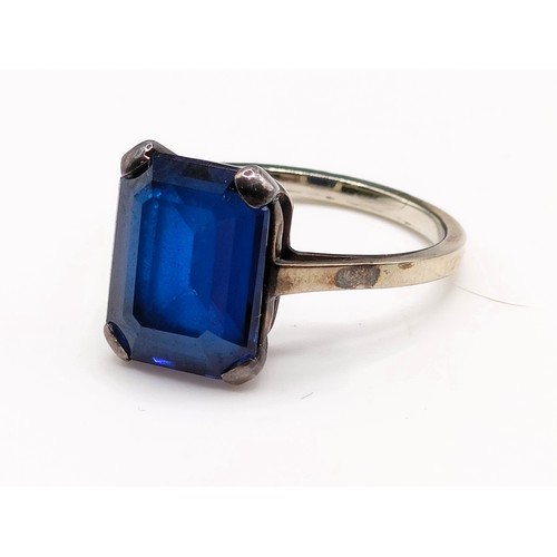 695 - A silver coloured metal and synthetic sapphire ring