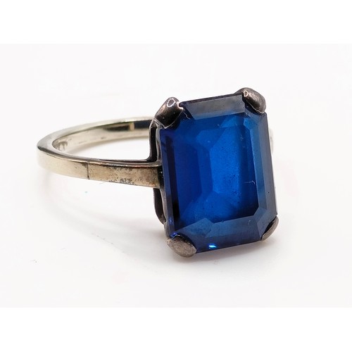 695 - A silver coloured metal and synthetic sapphire ring