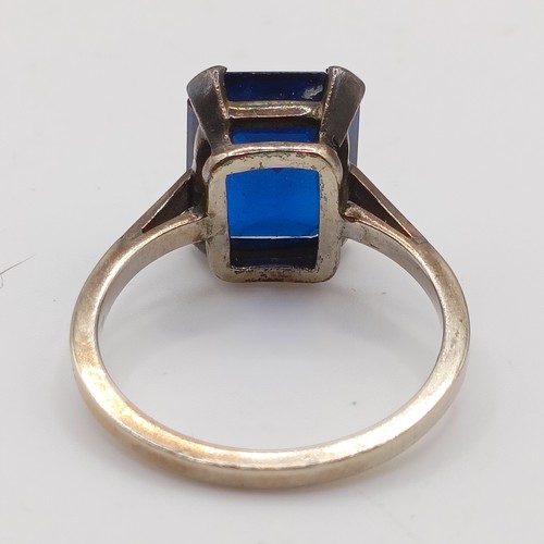 695 - A silver coloured metal and synthetic sapphire ring