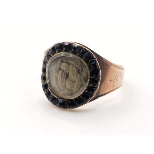 702 - A 19th century yellow coloured metal and red stone memorial ring, inset with a lock of hair, inscrib... 