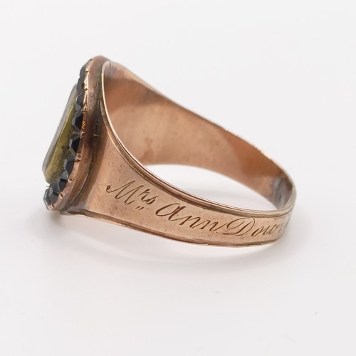 702 - A 19th century yellow coloured metal and red stone memorial ring, inset with a lock of hair, inscrib... 