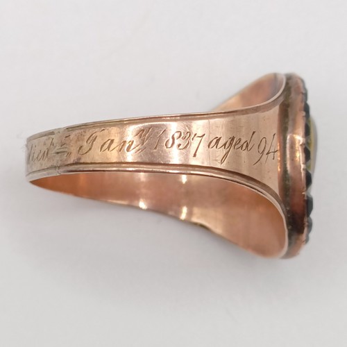 702 - A 19th century yellow coloured metal and red stone memorial ring, inset with a lock of hair, inscrib... 