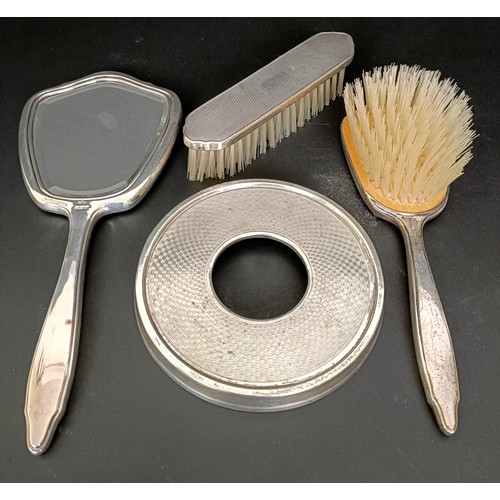 10 - A silver backed hand mirror, a pair of matching brushes and a silver mounted and bakelite lid, 12 cm... 