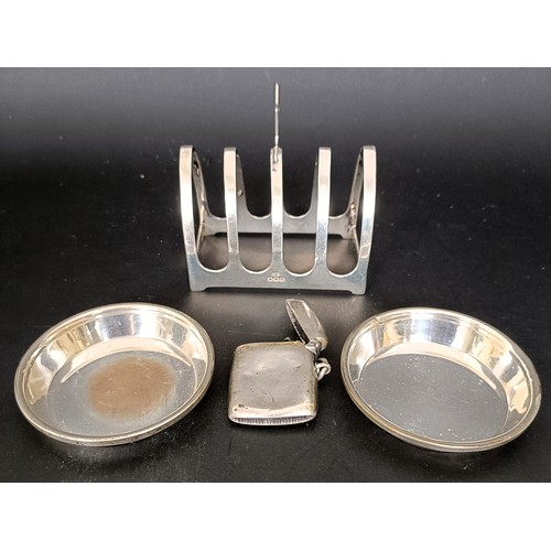 19 - A George V silver four division toast rack, 8 cm wide, a pair of silver pin dishes, and a vesta case... 