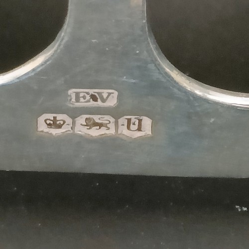 19 - A George V silver four division toast rack, 8 cm wide, a pair of silver pin dishes, and a vesta case... 