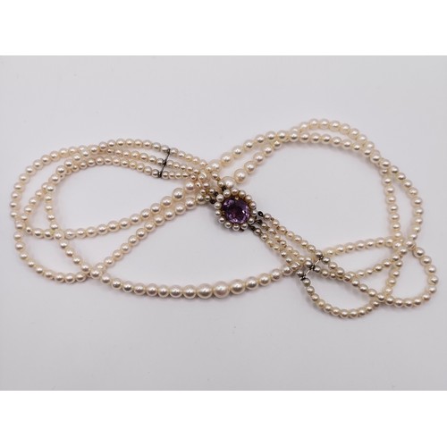 484 - A cultured pearl triple necklace, with a 9ct gold and amethyst clasp