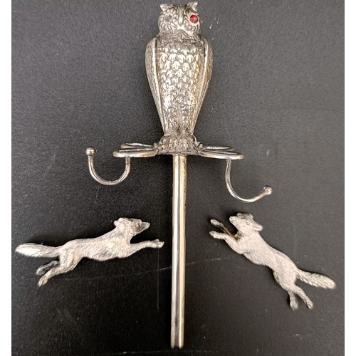 56 - A silver coloured metal ring holder, with an owl finial, lacking base, and a pair of silver coloured... 