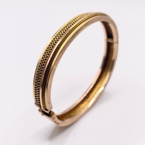 406 - An early 20th century yellow coloured metal hinged bangle, 13.4 g