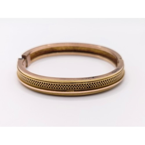406 - An early 20th century yellow coloured metal hinged bangle, 13.4 g