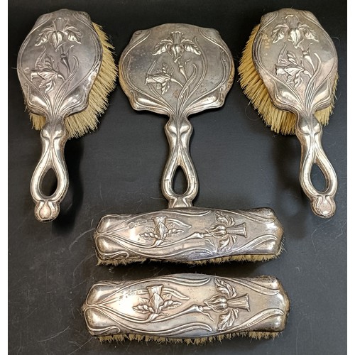 135 - An Art Nouveau style silver backed hand mirror, and four matching brushes, Birmingham 1905