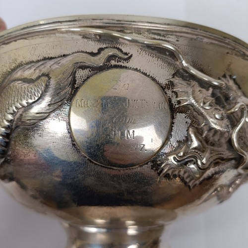 352 - A Chinese silver coloured metal pedestal bowl, decorated a dragon in high relief, inscribed and date...
