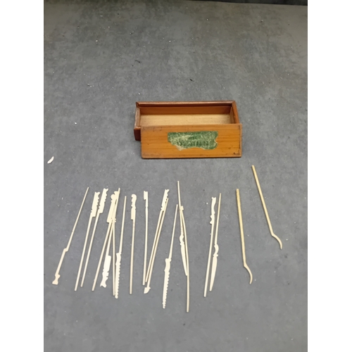 28 - An open-top rectangular wooden box containing approximately twenty-one slender implements, likely cr... 