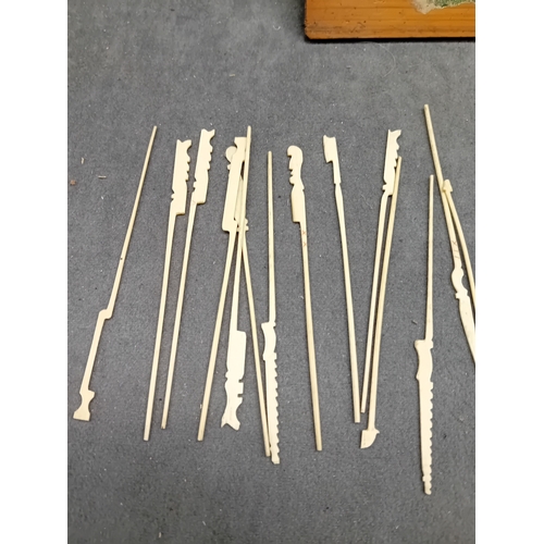 28 - An open-top rectangular wooden box containing approximately twenty-one slender implements, likely cr... 