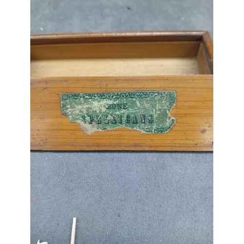 28 - An open-top rectangular wooden box containing approximately twenty-one slender implements, likely cr... 