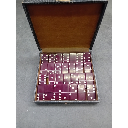 456 - A vintage cased set of red Bakelite and Catalin dominoes. The set features individual two-tone piece... 